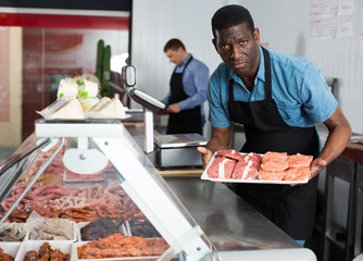 Two butchers arranging meat display