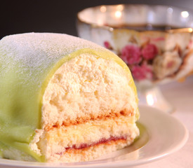 A princess cake with green marzipan, cream and a cup of coffee