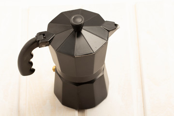 Italian black coffee maker on white wooden background