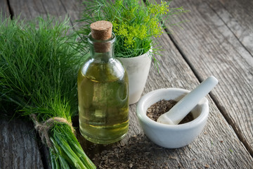 Wall Mural - bunch of aromatic fresh green dill, mortar of fennel seeds and dill oil bottle on wooden board.