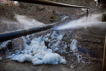 Water Pressure From A Large Pipe Over The River, In Winter