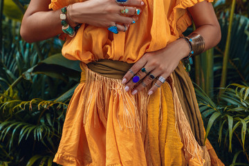 Wall Mural - close up of beautiful young fashionable woman hands with stylish boho accessories on natural tropical background