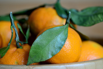 Ripe tangerines with leaves on a wooden background