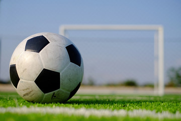 Soccer football on green grass field and goal post