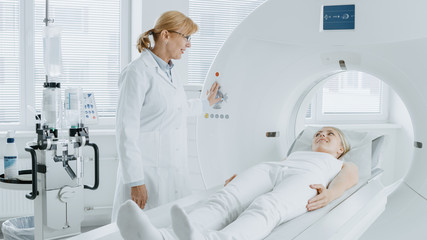 In Medical Laboratory Radiologist Controls MRI or CT or PET Scan with Female Patient Undergoing Procedure. High-Tech Modern Medical Equipment. Friendly Doctor Chats with Patient.