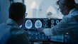 © Gorodenkoff - In Control Room Doctor and Radiologist Discuss Diagnosis while Watching Procedure and Monitors Showing Brain Scans Results, In the Background Patient Undergoes MRI or CT Scan Procedure.