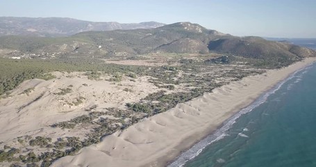 Wall Mural - High altitude reversing aerial drone video of coastal Patara sand dunes, beach on Mediterranean Sea, mountain landscape and distant Lycian ruins in Turkey. 4k at 23.97fps