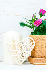 Decorative heart, pink roses and candles on white wooden backgro