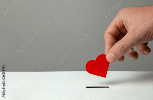 Fotografía Man’s hand places heart in the donation slot