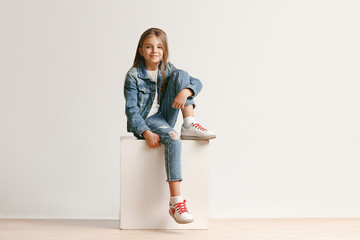 full length portrait of cute little teen girl in stylish jeans clothes looking at camera and smiling