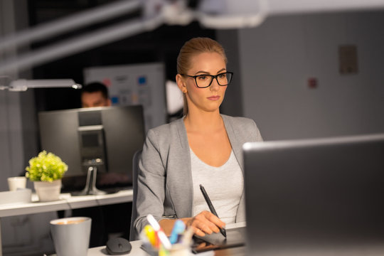 business, technology, design and people concept - young creative woman or graphic designer with laptop computer working by pen tablet late at night office