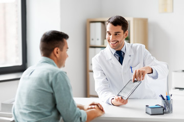 medicine, healthcare and technology concept - doctor with tablet pc computer and male patient talking at medical office in hospital