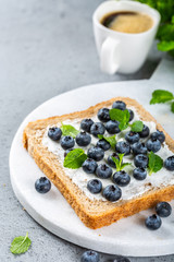 Wall Mural - Delicious open sandwich with goat cheese and blueberries for breakfast or lunch on marble board. Food background with copy space.