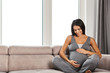 © Drobot Dean - Healthy pregnant woman indoors at home sitting posing.