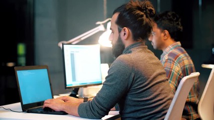 technology, deadline and programming concept - programmer team with computers working together late at night office