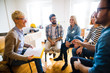 © Dusan Petkovic - Group of people sitting in a circle on group therapy. Looking at their therapist and listening ti her story.