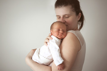 Gentle mother holds sleeping newborn baby