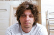 © familylifestyle - Sleepy shaggy young man looks at the mirror in bathroom in the morning.