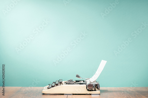 Fotografía Retro classic typewriter from circa 1950s with sheet of paper on wooden desk front aquamarine wall background