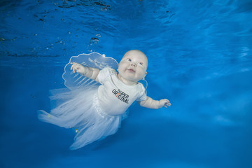 Little funny fairy under water on a blue water background.  Healthy family lifestyle and children water sports activity. Child development, disease prevention