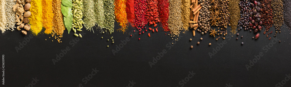 Variety condiments and herbs scattered on background of  black table. Heaps Indian spices on chalkboard with empty space. - obrazy, fototapety, plakaty 