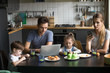© fizkes - Parents using laptop and smartphones having breakfast with children, bored father writing email, searching internet while mother, son and daughter using phone apps, ignore, family gadget addiction