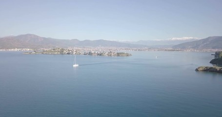Wall Mural - Forward aerial drone video above ocean water passing sailboat towards Fethiye Adasi island in natural harbor with scenic mountain landscape view behind Fethiye, Turkey. 4k at 23.97fps