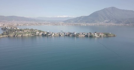 Wall Mural - Aerial drone video tracking left Fethiye Adasi Island and distant downtown cityscape with mountain background of Fethiye city in Turkey. 4k at 23.97fps