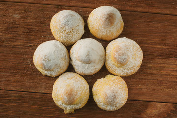 cottage cheese biscuits in breadcrumbs of powdered sugar on a wooden background