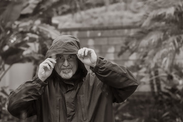 Wall Mural - Portrait of mature man outside in the rain wearing hood and rain coat