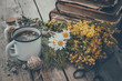 Enameled mug of healthy tea, bunches of medicinal herbs and stack of old books. Herbal medicine.