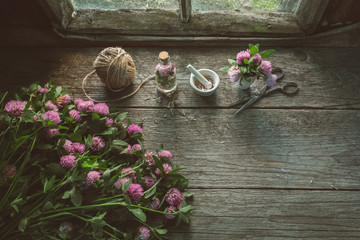Wall Mural - pink clover flowers, mortars, clover tincture or infusion, scissors and jute on old wooden table ins