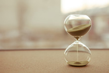 Sand Running Through The Bulbs Of An Hourglass Measuring The Passing Time In A Countdown To A Deadline, On A Blur Background