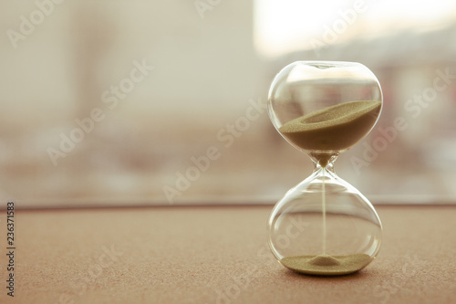 Cuadros en Lienzo Sand running through the bulbs of an hourglass measuring the passing time in a c