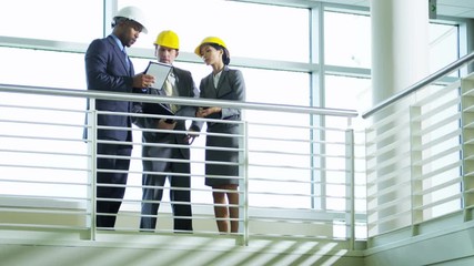 Professional African American male architect showing business clients prospective new site using wireless tablet technology  