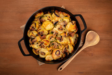 Wall Mural - A photo of a braiser with cooked vegetables, potato, green peas, mushrooms, shot from above on a dark rustic background with copy space, a vegan dinner