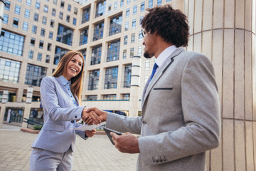 Businessman and businesswomen shaking hands outside office