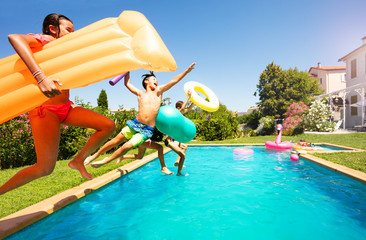 Funny teens with swim tools jumping into the pool