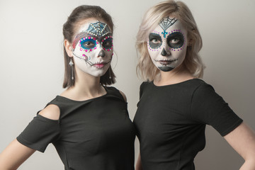 Two girls with make-up skeleton on their faces. Halloween.