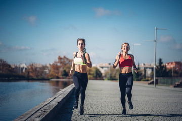 Wall Mural - Two beautiful women perform outdoor exercise in park.