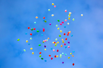 balloons are flying in the blue sky. festive multi-colored helium bubble in flight.