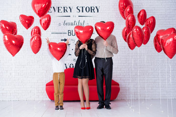 Family hiding faces behind balloon.