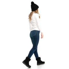 Beautiful woman in sweater jeans hat cold goes walking on white background isolation back view