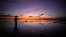 Silhouette Of A Balinese Man In A Conical Bamboo Hat Fishing At Sunrise 