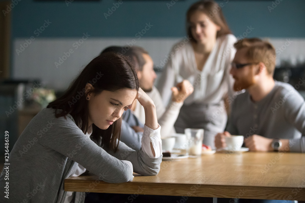 Upset young girl sit alone at coffee table in cafe feeling lonely or offended, sad female loner avoid talking to people, student outsider suffer from discrimination, lacking friends or company - obrazy, fototapety, plakaty 