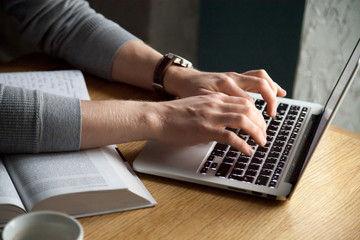 close up of man typing at laptop studying out in cafe, busy guy working at computer at cafe table wi