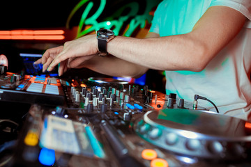 DJ turntable console mixer controlling with two hand in concert nightclub stage.