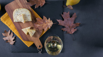 Wall Mural - A glass of white wine served with cheese in a cutting board on d