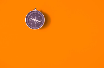 black compass on orange background, equipment for travel, tourism and business, top view and copy sp