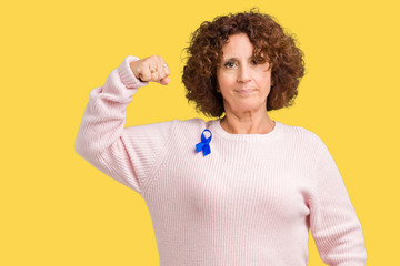 Sticker - Middle ager senior woman wearing changeable blue color ribbon awareness over isolated background Strong person showing arm muscle, confident and proud of power